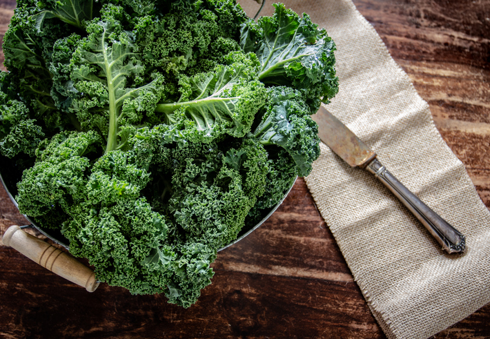 Kale in basket and knife on wooden  background top view on daylight superfood vegetables