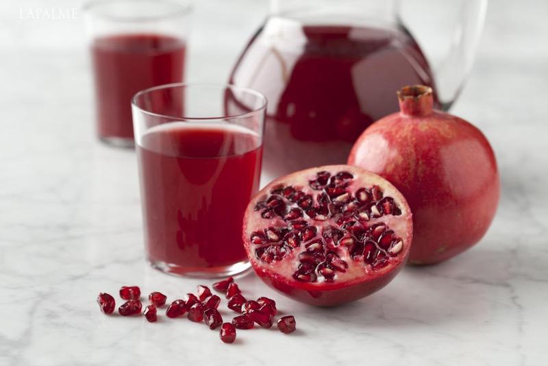 halves-pomegranate-with-seeds-and-pomegranate-juice-on-marbled-surface